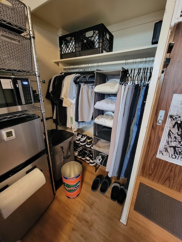 Boy dorm room open closet with storage organization
