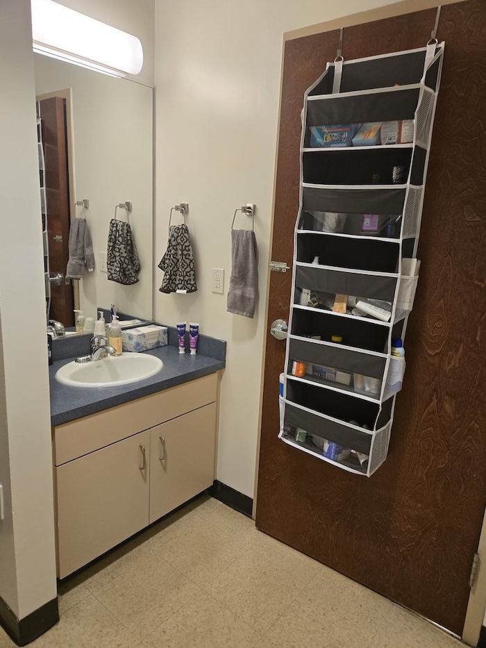 Boys dorm room with private bathroom and over door storage organizer